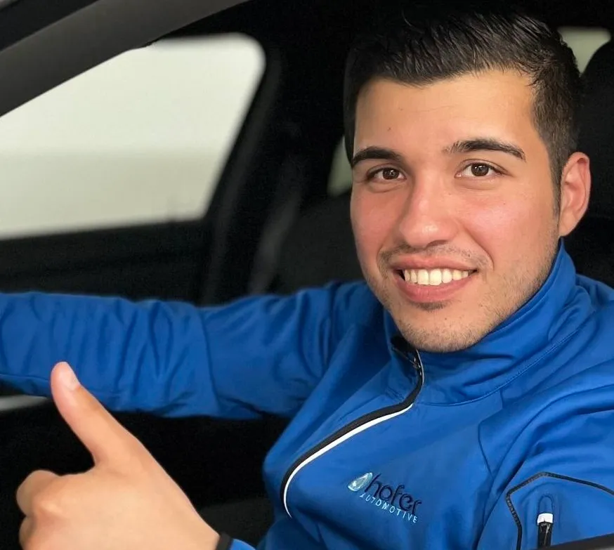 Mann in Hofer-Automotive-Jacke am Steuer, Daumen hoch